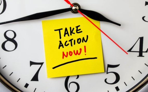 Sticky note with the text "Take Action Now!" on top of a clock