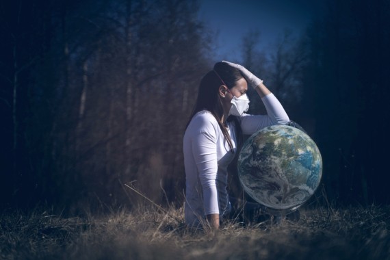 Woman wearing a mask holding the world in her lap while sitting outside